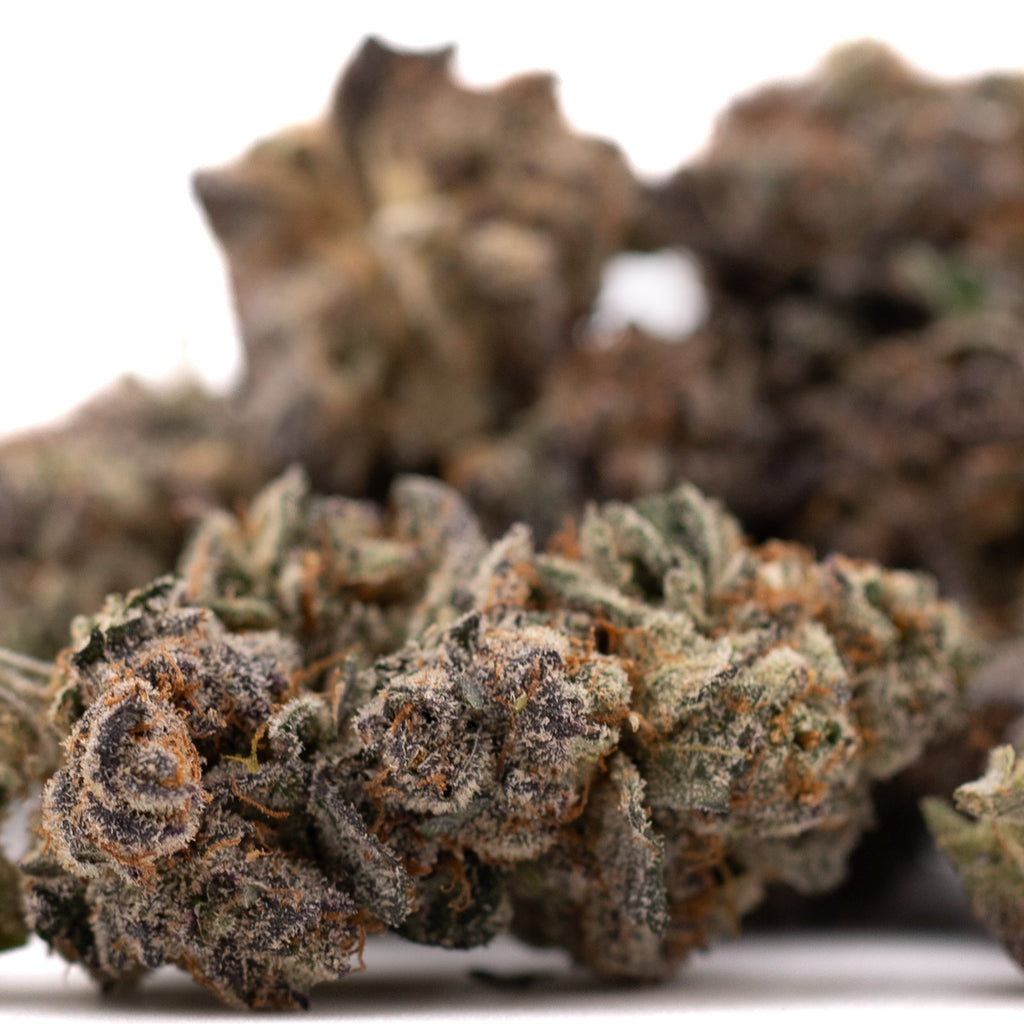 Close-up of Poppin Bottlez indoor THCa flower buds with vibrant green purple hues and frosty trichomes